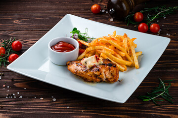 Fried chicken fillet with French fries, onion, cherry tomatoes and ketchup, lunch.