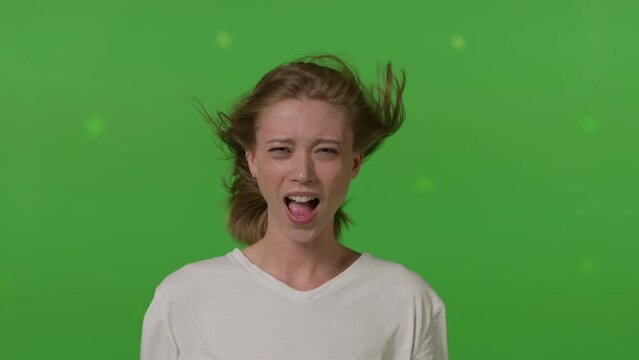 Caucasian girl in front of TV screen getting blown away. Cinema concept with chroma key.