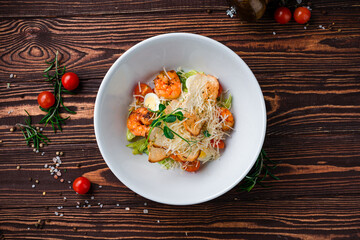 Caesar salad with shrimps, parmesan cheese, eggs, lettuce, tomatoes and croutons.
