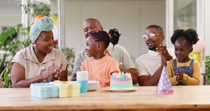 Birthday, children party and applause with a black family in celebration of a girl child in their home. Parents, grandparents and kids clapping while blowing candles on a cake at a milestone event