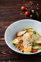Caesar salad with chicken, parmesan cheese, eggs, lettuce, tomatoes and croutons, Italian cuisine.