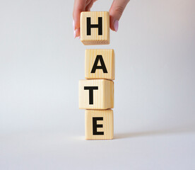 Hate symbol. Concept word Hate on wooden cubes. Businessman hand. Beautiful white background. Business and Hate concept. Copy space.