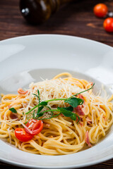 Spaghetti with bacon, cherry tomatoes, parmesan cheese and herbs, closeup.