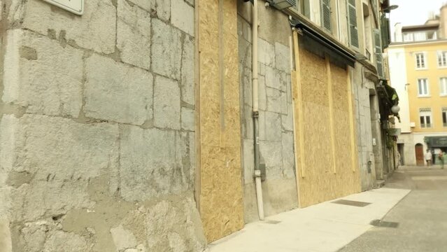 Broken storefronts covered with wooden panels after night unrest in city centre of Grenoble, France