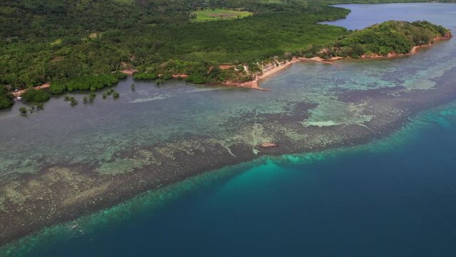 Aerial drone footage of mainly Recife in Philippines. View of the recife along the coastline with beaches and jungle. Film movement is trucking plus a bit of pan.