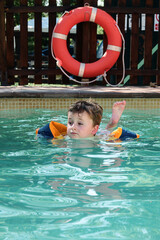little boy with float swimming in a pool. vacation time. summer