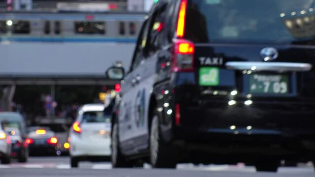 SHIBUYA, TOKYO, JAPAN - JUNE 2023 : View around Shibuya crossing in daytime. Car passing by on the road. Street traffic, vehicle and transportation concept 4K video.