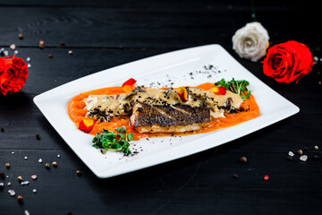 Fried white fish with carrot puree, mushrooms in sauce, truffles and microgreens.