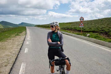 Fit female cyclist wearing cycling gear.Cyclist is depicted taking a break during her training and...