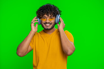 Happy indian man in headphones listening music and dancing disco fooling around having fun...
