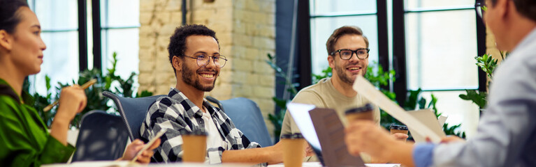Sharing fresh ideas. Group of young multiracial people sitting at the table in coworking space and...