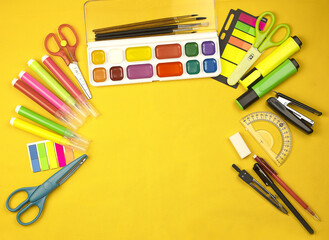Yellow background with copy space and end school items. Back to school. Paint brushes, markers, pencils, drawing background, compasses, scissors. High quality photo