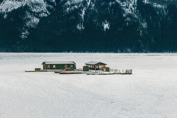 Green cabin in the middle of a frozen Lake Minnewanka