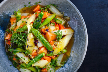 Green and white asparagus glazed with papaya in sweet vinaigrette served as top view in a design plate with text space right
