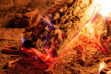 Burning log in flames in a campfire close-up