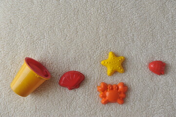 Fototapeta na wymiar textura de areia com brinquedos de praia, estrela, concha, peixinho