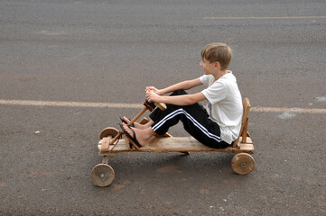 garoto feliz  brincando com carrinho de madeira rústico na rua 