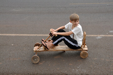 garoto feliz  brincando com carrinho de madeira rústico na rua  © Alexandre