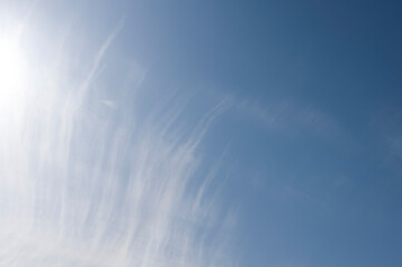 Blue sky abstract background with white feather clouds and sunshine