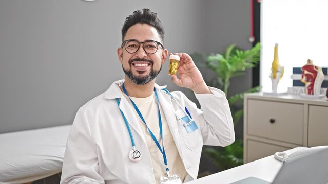 Young latin man doctor using laptop holding pills at clinic