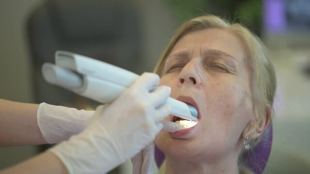 The dentist examines the teeth of an elderly lady in a modern clinic, providing her with comprehensive dental care