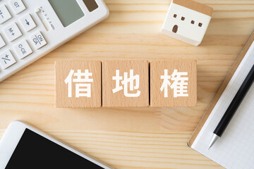 借地権と書かれたブロック、電卓、スマホ、ミニチュアの家