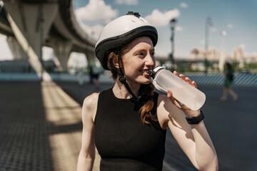 Drinks clean water uses a plastic bottle, break time, a young woman in a helmet happy training...