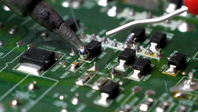 Close-up of repairman soldering on circuit board.