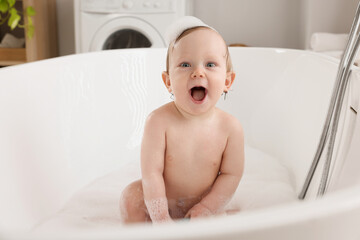 Cute little baby bathing in tub at home