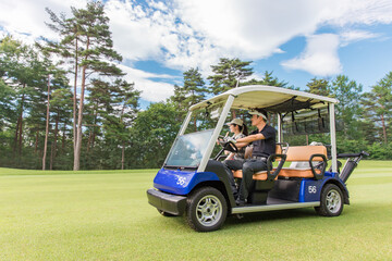 ゴルフ場でゴルフカートに乗るゴルファーの男女
