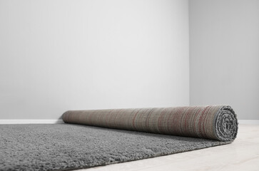 Rolled grey carpet on floor in room, closeup