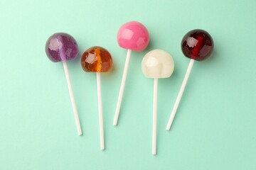 Tasty lollipops on turquoise background, flat lay