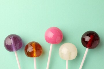 Tasty lollipops on turquoise background, flat lay. Space for text