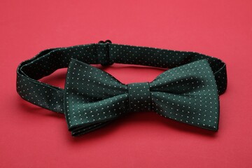 Stylish black bow tie with polka dot pattern on red background