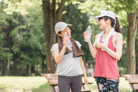 ダイエットのために有酸素運動・ウォーキングをする若いアジア人女性たち（水分補給・休憩）
