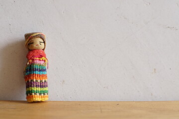 Guatemalan worry doll or quitapenas on white and wooden background