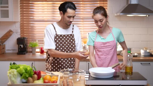 Happy Asian couple cooking dinner together in kitchen.