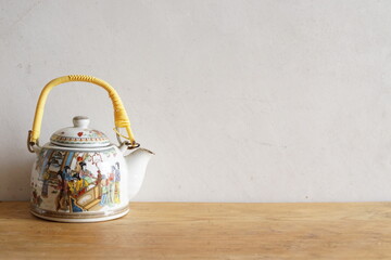 Vintage chinese ceramic tea pot on white and wooden background