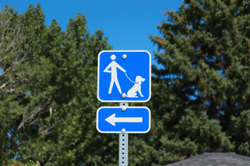 A blue sign at a rest stop showing travelers an area where they can take their dogs on a leash. 