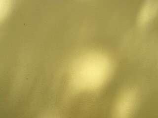 Yellow wall background with blurred circles light from the sun through tree branches.  Copy space for your text.