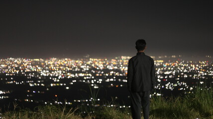 Fototapeta premium The man stand on the background of the city lights. night time