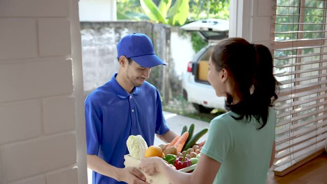 Young Asian woman receiving a package at the doorstep from a courier.