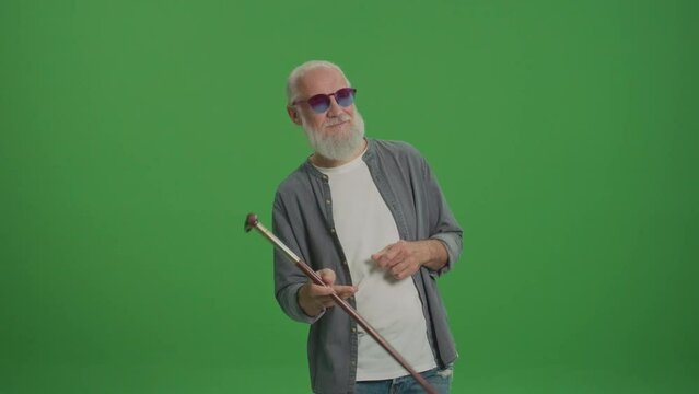 Green Screen. A Happy Old Man in the Funny Glasses Dancing with a Stick. Smiling Elderly Man Enjoy His Life. Modern Elderly People Concept. Retirement with Pleasure and Without Worries.