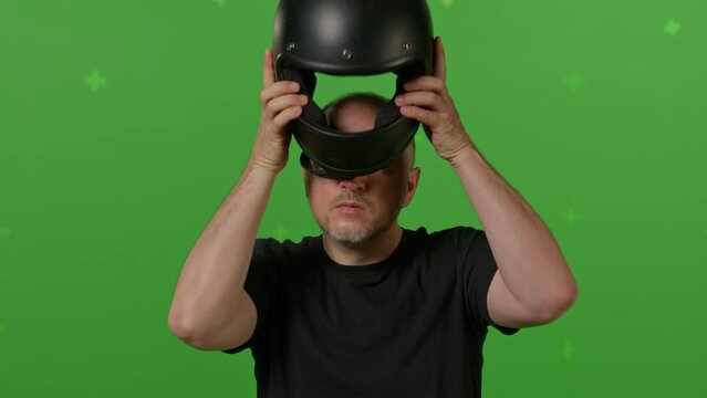 Close-up of Man motorcyclist take off his helmet on green screen chroma key background. People, modern lifestyle and youth concept.