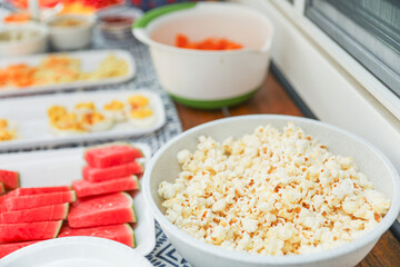 potluck spread of fresh veggies, fruits, and dips, complemented by crunchy chips, popcorn, and eggs, symbolizing diversity, nourishment, and shared experiences