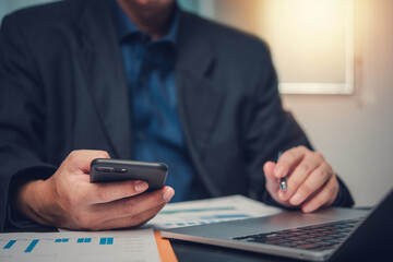 Fototapeta premium Businessman Analyzing data on laptop and graph chart for financial planning report diagram marketing on desk.