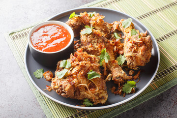 Thai Street Food Hatyai Fried Chicken with sweet chili sauce and crispy onions close-up on a plate on the table. Horizontal