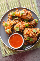 Thai Southern Fried Chicken with crispy shallots and sweet chili sauce close-up on a plate on the table. Vertical top view from above