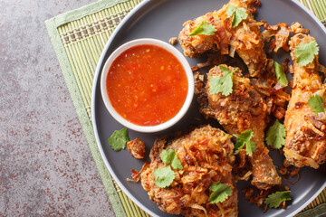 Crisp and Juicy Thai Fried Chicken marinated with cilantro, garlic and Asian seasonings close-up on a plate on the table. Horizontal top view from above