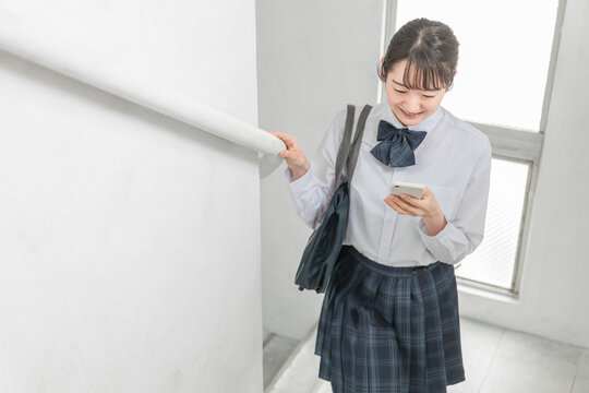 学校の校舎内・廊下・階段を歩く笑顔の高校生・中学生・女子高生（制服・学生服）

